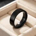 Macro view of a 6mm polished black stainless steel band ring in a beige jewelry box. - Size 5 / Black