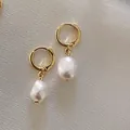 Gros plan de boucles d'oreilles perles baroques élégantes en acier titane plaqué or 18k - Style Minimaliste à Perle Unique