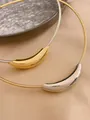 Primer plano de gargantillas de acero inoxidable con colgantes curvos en oro y plata. - Gargantilla de Plata + Colgante de Oro