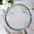Gedetailleerd overzicht van handgemaakte turquoise kralenketting met gouden accenten op stof - Ketting / 38+5cm / Turkoois Tussenkralen