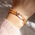 Close-up of stacked handmade beaded bracelets with natural orange semi-precious stones. - Brown & Gold Spaced Bracelet