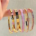 Vue détaillée de cinq bracelets dorés ornés de cœurs roses et de cristaux étincelants - Ensemble Émail Cœur Rose