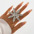 Gros plan détaillé d'une bague fleur de soleil métallique élégante sur une main - Style de Fleur Rayonnante à Sept Pétales (X2545) / Argent