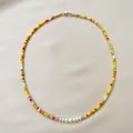 Bohemian rainbow seed bead necklace with irregular freshwater pearls on pink fabric. - Short Choker Length / Yellow Red