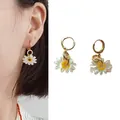 Charmante witte madeliefjes oorbellen met goudkleurige ringen, getoond op een model - Madeliefje Stijl