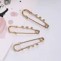 Detailopname van 6 cm gouden veiligheidsspelden met drie lussen voor doe-het-zelf sieraden. - Per stuk verkocht / Goud
