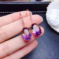 Gros plan de boucles d'oreilles pendantes en or rose avec pierres ovales violettes - Paire de boucles d'oreilles avec pierres colorées