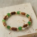 Primer plano de una pulsera artesanal con piedras naturales verdes y cuentas madera. - Pulsera de cuentas tubulares color madera