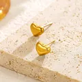 Close-up of golden heart-shaped stud earrings on a textured stone surface - Heart Stud / Gold