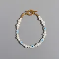 Detailed view of an Evil Eye charm and pearl necklace with a gold toggle clasp. - Style M Bracelet / One Size / 17+3cm