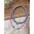 Detail view of turquoise and pink beaded necklaces with evil eye charms on bamboo mat. - Style T / One Size / 38+5cm / Turquoise Mix