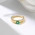 Close-up of personalized gold-tone ring with vertical texture and emerald-green stone detail. - US 7 / Gold Green Zirconia