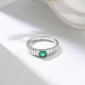 Primo piano dettagliato di un anello in acciaio al titanio con gemma verde tonda. - Argento con strass verdi