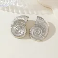 Gros plan de boucles d'oreilles clous en forme de coquillage argenté avec textures. - Boucles d'Oreilles en Argent
