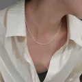 Macro view of minimalist silver bead chain necklace worn with a white silk shirt - Round Bead O-Chain Necklace (XL8103Y) / Steel