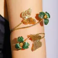 Close-up detail of an adjustable gold-tone arm cuff with green enameled flowers and butterflies. - Butterfly Flower Style (DZ-736) / Green Flower Butterfly (Gold Armlet)