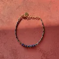 Detail view of blue natural stone beaded bracelet with golden heart charm on red surface - Dark Blue Cylindrical Beaded Style with Heart Tag (Bracelet 4) / 17+3cm