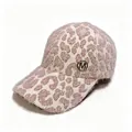 Close-up detail of a soft leopard print plush baseball cap with a metallic M logo. - Pink