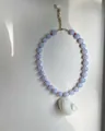 Detailweergave van een handgemaakte ketting met een witte schelphanger en paarse kralen. - Blauwe Kralenstijl / 38+5cm / Blauw