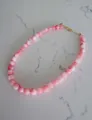 Close-up van roze schelpkralen en gouden sluiting op een marmeren achtergrond - Roze Natuurlijke Ronde Kralen Ketting / 38+5cm