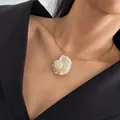 Goudkleurige choker halsketting met natuurlijke schelphanger gedragen door een model. - Stijve Choker Murex Hanger / 38+5cm