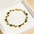 Elegant gold-tone vintage bracelet featuring emerald green gemstones in flower vine design - Gold with Green