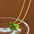 Macro view of a minimalist irregular cut green gemstone pendant with a gold chain. - Grass Green