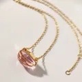 Close-up of elegant gold necklace with irregular faceted pink crystal pendant - Transparent Pink