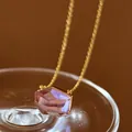 Detailed macro view showing the faceted purple gemstone pendant on a delicate gold chain - Amethyst