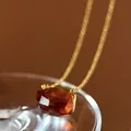 Close-up of an irregular cut amber crystal pendant necklace with an elegant gold chain - Amber
