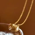 Macro view of a minimalist amber crystal pendant featuring unique irregular facets. - Champagne