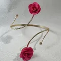 Detail eines eleganten goldenen Armreifs mit zwei pinkfarbenen Stoffrosen und Struktur. - 33521-ab-ros-EP