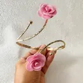 Detailansicht eines goldenen Metall-Armreifs mit zwei rosa Stoffrosen verziert. - 33521-ab-pink-EP