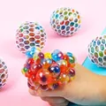 Hand squeezing a rainbow mesh squishy grape ball stress relief toy with colorful water beads - Mesh Colorful Bead Ball (1 Piece)