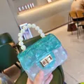 Dettaglio borsa jelly in PVC blu con manico in perle e motivo a rombi trapuntati - verde trasparente