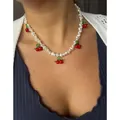 Détail d'un collier en perles d'eau douce avec des pendentifs cerises sur un mannequin - 43cm / Collier en perles de cerise en verre de lampe rouge