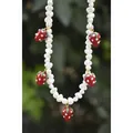Gros plan d'un collier en perles d'eau douce avec des breloques fraises rouges de détail - 43cm / Collier en perles de fraise en verre de lampe rouge