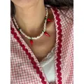 Détail d'un collier de perles d'eau douce avec breloques piment en verre sur modèle. - 43cm / Collier en perles de piment en verre de lampe rouge
