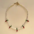 Gros plan d'un collier de perles avec des breloques piment en verre et fermoir doré - 43cm / Collier ras du cou en perles de piment en verre de lampe rouge (style court)