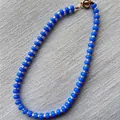 Detalle de cuentas de ábaco azules y perlas blancas sobre un fondo de tela texturizada. - Collar H / Talla única / 43cm / Azul