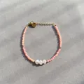 Vue détaillée du bracelet en pierre naturelle rose avec perles et breloque cœur doré - Style patchwork de petites perles rondes roses et trois perles / Taille unique / 17+3cm / Rose