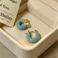 Detailweergave van vintage turquoise oorringen in een elegante beige sieradendoos - Micro-Pave Turkoois U-Vorm Stijl (E2533) / 1.7cm / Goud