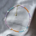 Close-up of colorful beaded necklace with natural pearls and a gold heart charm - Short Choker Length / Purple Orange Blue Pink