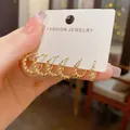 Set van zes elegante goudkleurige gedraaide oorringen op een wit sieradenkaartje - Gouden Spiraal Stijl