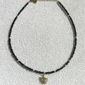 Collar artesanal con colgante de sol, piedras naturales negras y detalles dorados - Estilo Medio Sol de Fragmentos Negros