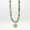 Detalle de un collar vintage de piedras naturales verdes con un colgante de sol dorado. - Estilo Colgante Sol de Cuentas Verdes