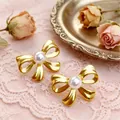Elegantes pendientes de lazo de metal dorado con perla sobre fondo vintage romántico - Dorado