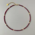 Close-up of faceted dark red natural stone necklace with gold spacer beads and heart charm - Necklace / 38+5cm / Red Brown