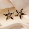 Gros plan de boucles d'oreilles étoile de mer en acier doré avec taches en émail noir - Boucles d'Oreilles Clous Étoile de Mer à Points Noirs (2188)