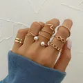 Gold-toned knuckle ring 7-piece set featuring pearl, wave, and infinity designs on a hand - Gold Pearl Infinity Symbol Knuckle Ring 7-Piece Set (51186) / Gold